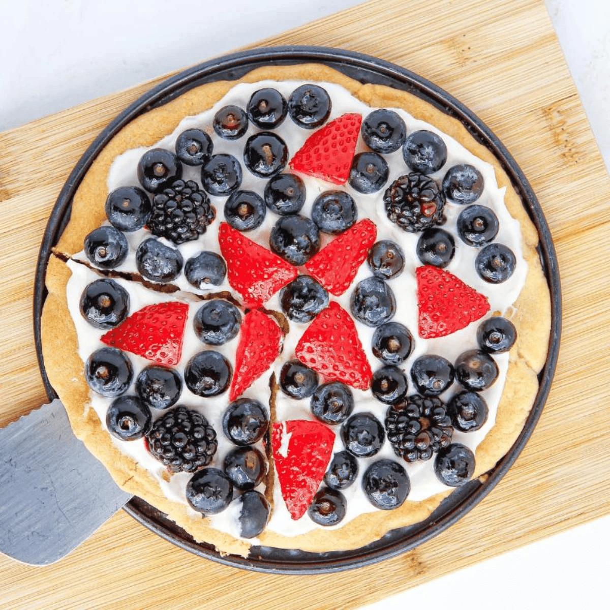 A colorful Air Fryer Sugar Fruit Pizza topped with fresh berries and creamy frosting on a plate.
