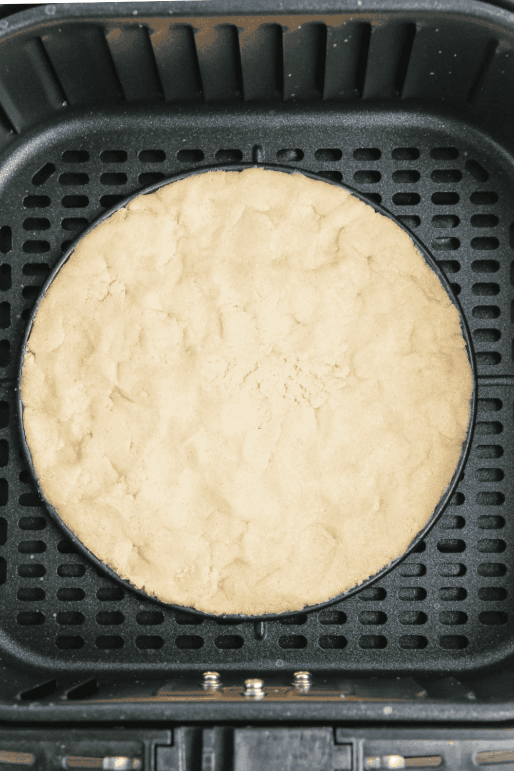 Air fryer basket with cookie dough in a pan, cooking until golden brown at 320°F.