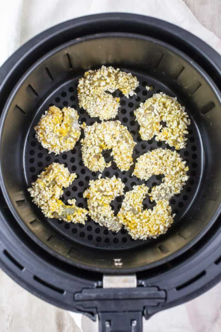 Shrimp coated in seasoned flour mixture resting in a bowl in the refrigerator.