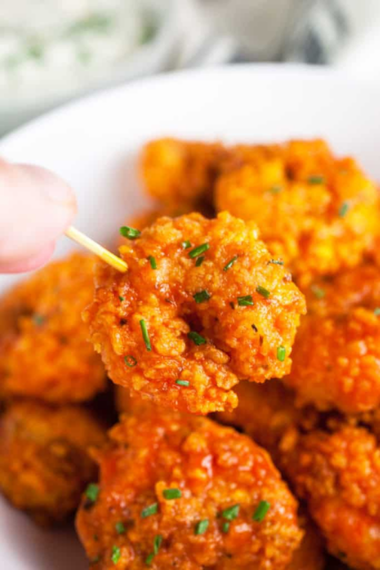 Crispy air fryer Hooter's style buffalo shrimp served on a plate with buffalo sauce.