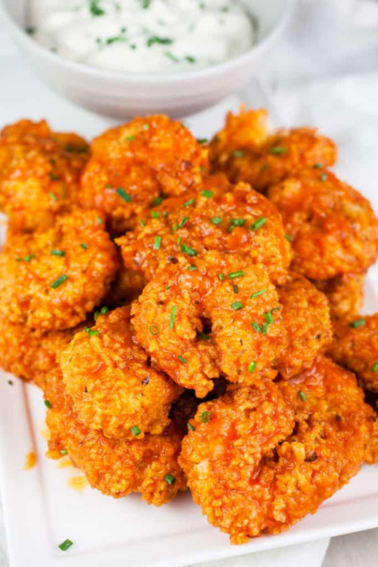 Air-fried buffalo shrimp garnished with parsley, served with celery sticks.