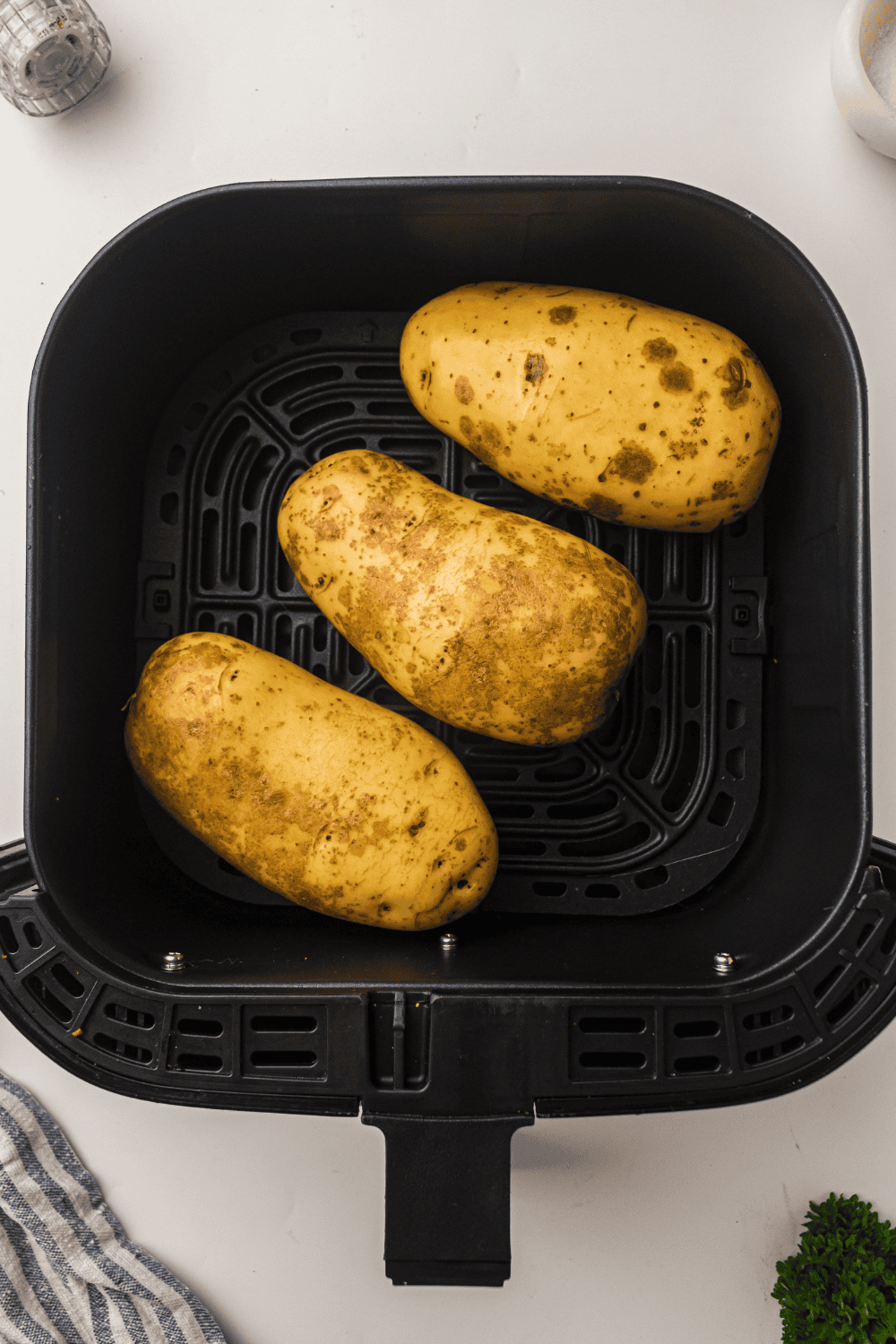Potatoes being washed and scrubbed with a vegetable brush before air fryer cooking.