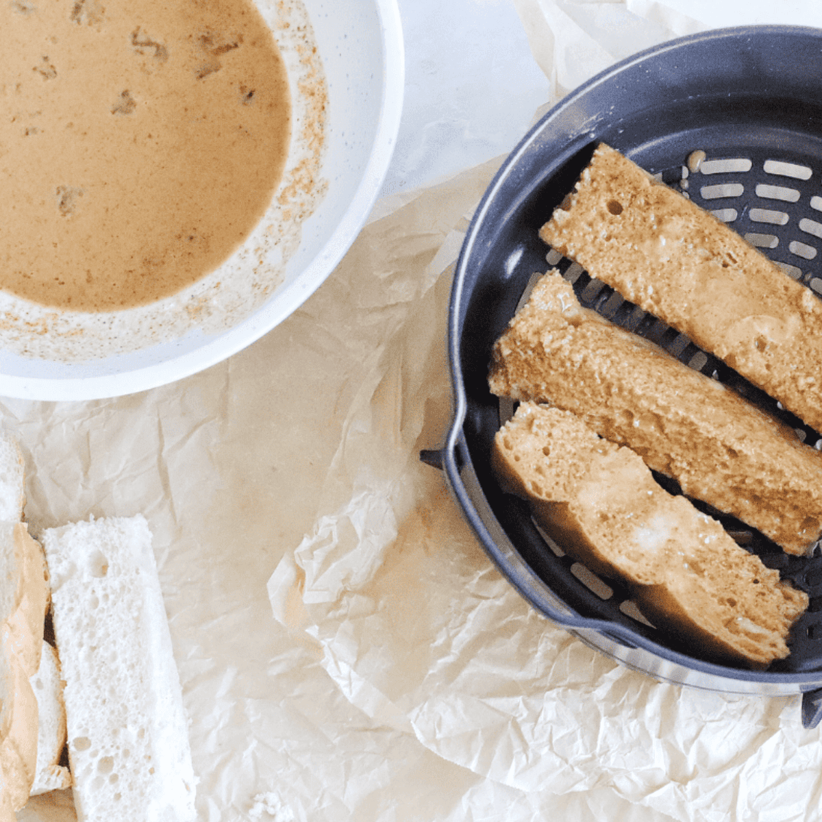 French toast slices dipped in batter and cooking in Ninja Foodi, flipped halfway for even golden brown.