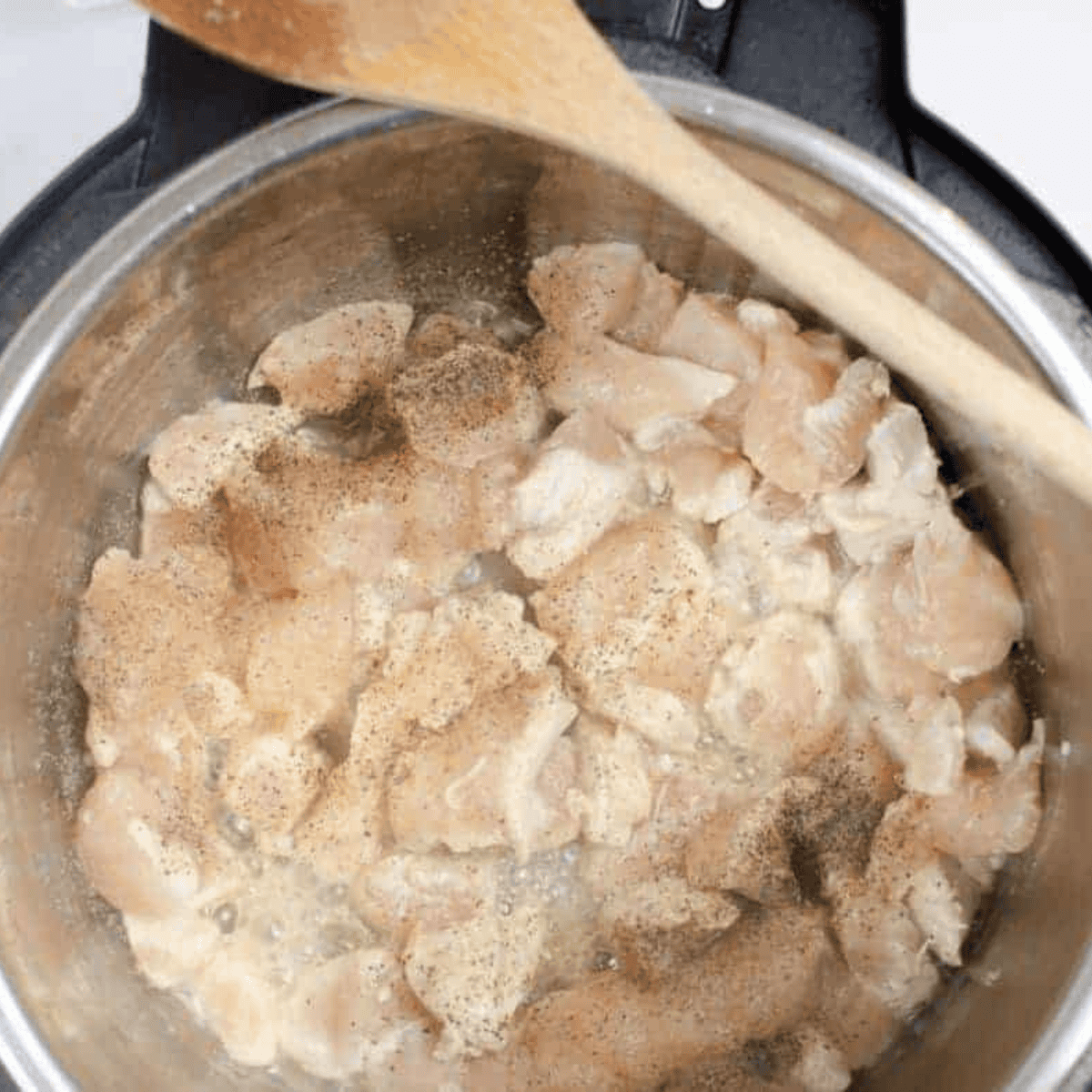 Slow cooker filled with chicken, chopped onions, garlic, and ginger.