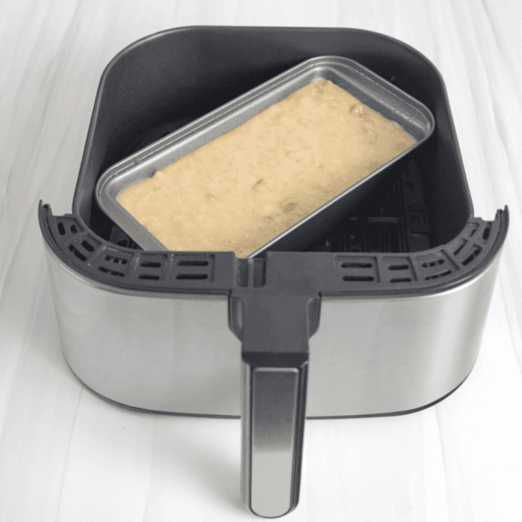 Pouring almond chocolate banana bread batter into greased mini loaf pans, cooking in air fryer until golden and toothpick comes out clean.