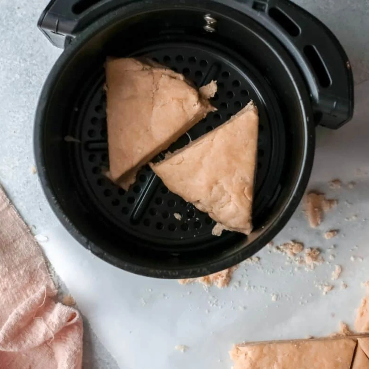 Unbaked apple scones spaced apart on parchment in an air fryer basket