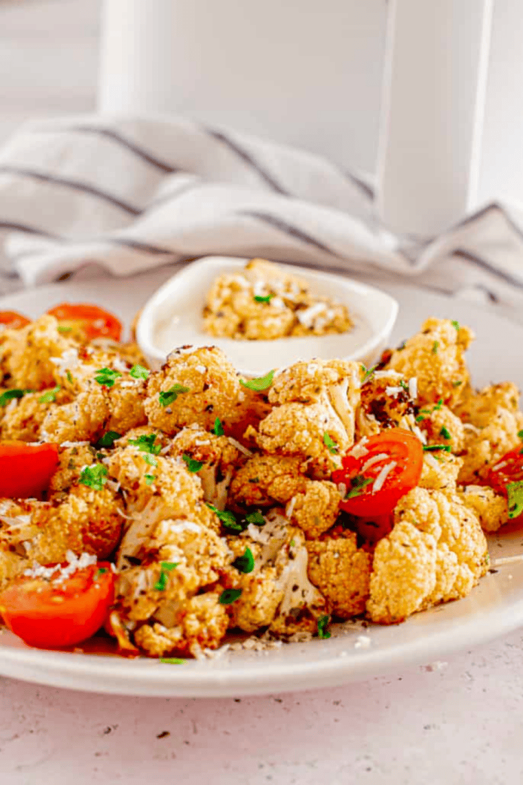 Golden air fryer cauliflower florets mixed with roasted cherry tomatoes, ready to serve in a bowl.