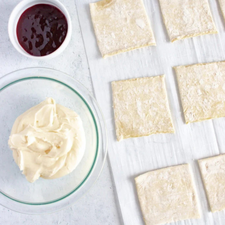 Puff pastry squares topped with cream cheese filling and raspberry jam before folding