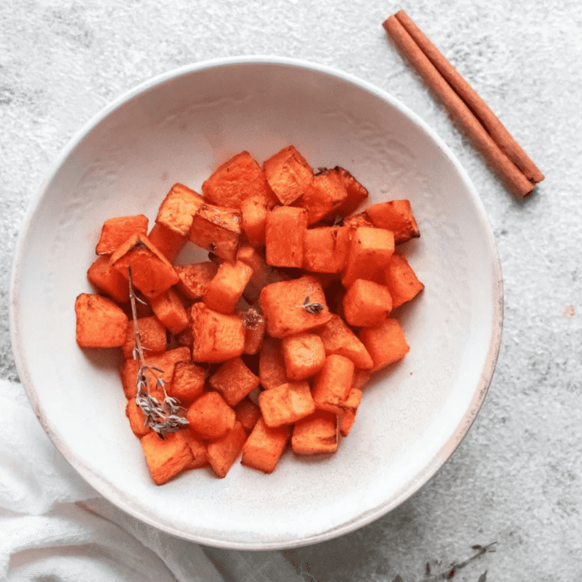 Diced air fryer roasted pumpkin with crispy caramelized edges in a white bowl, seasoned with smoked paprika and cinnamon