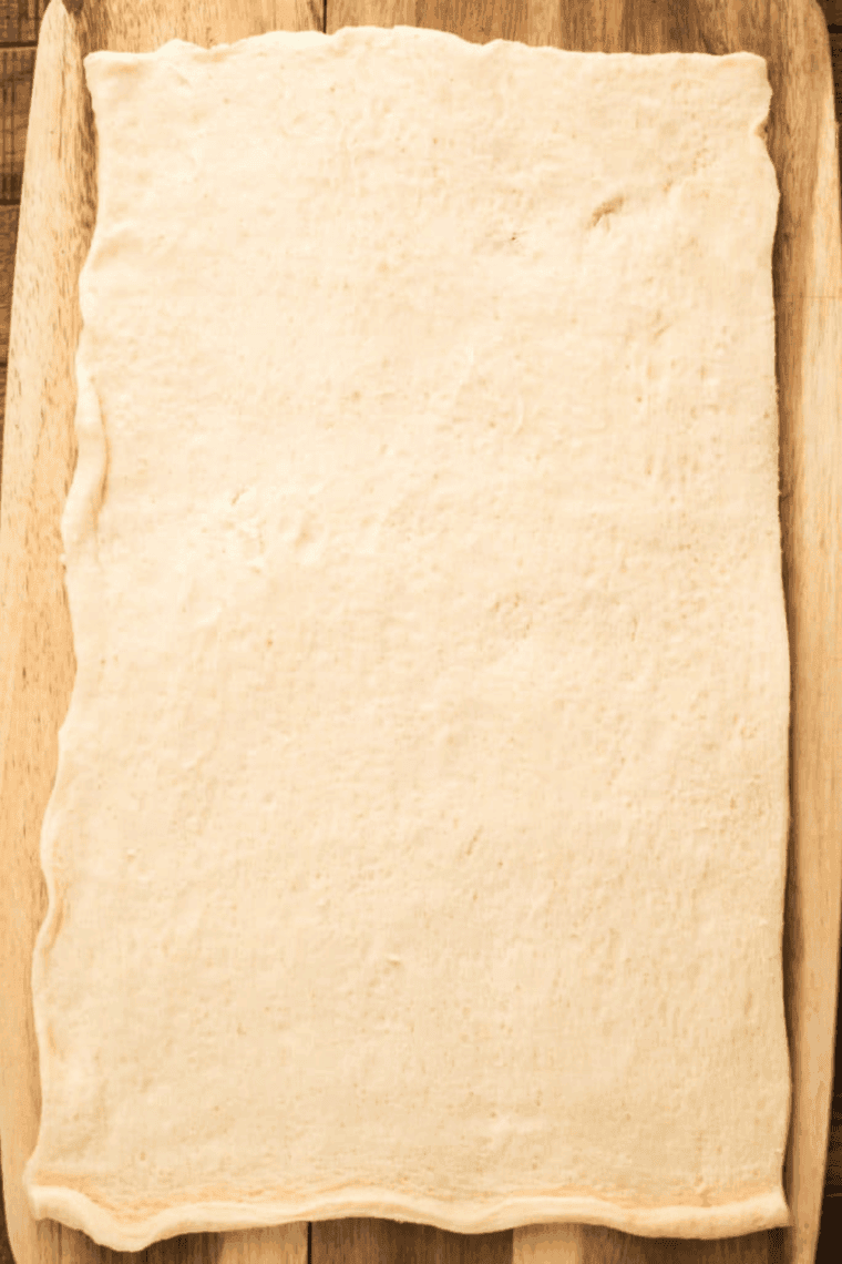 Preheating the air fryer to 390°F while preparing the canned pizza dough on a lightly floured cutting board.