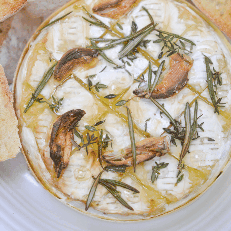 Golden air fryer camembert with melted center, fresh herbs, and honey drizzle served with crusty baguette slices.