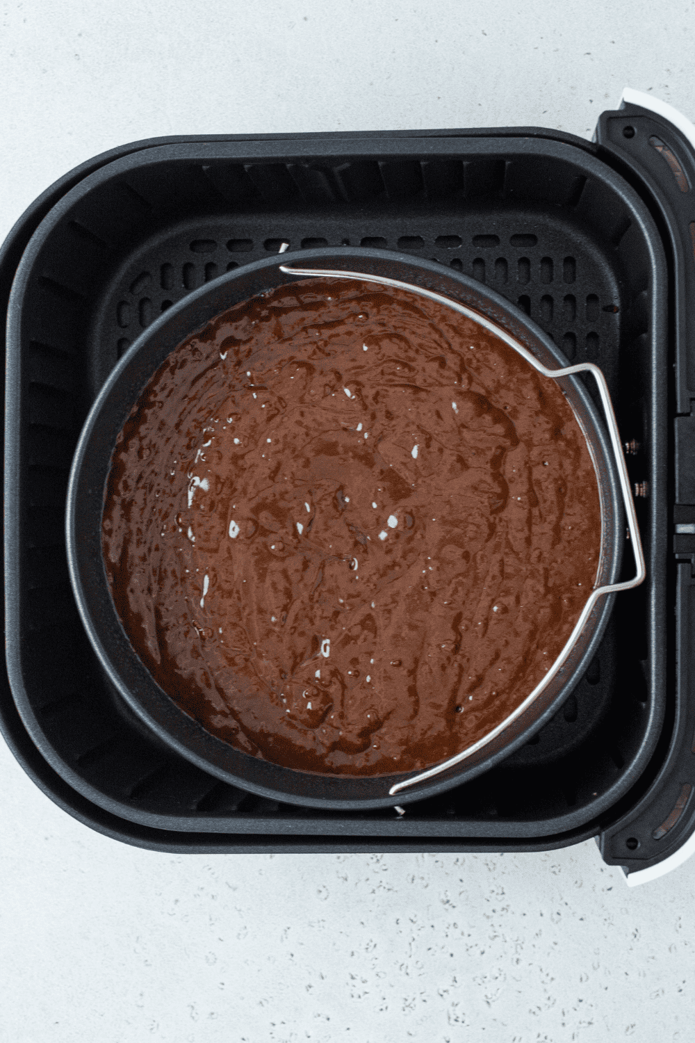 Air fryer baking pan with chocolate cake, set to 320°F, baking until toothpick comes out clean.