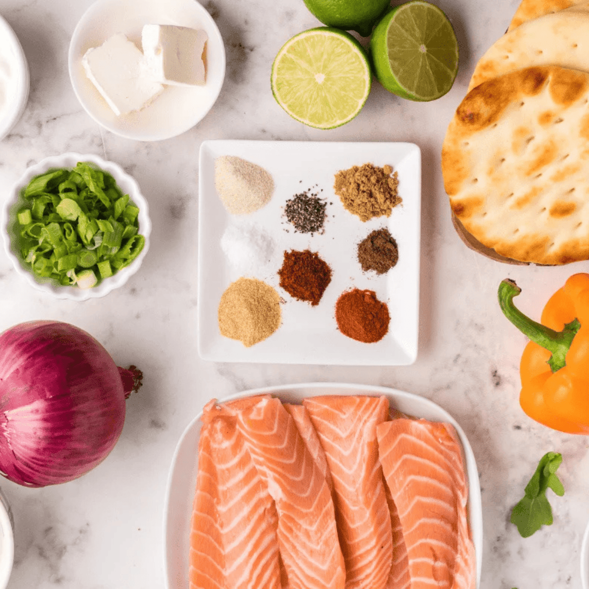 Ingredients for air fryer salmon flatbread: salmon fillet, naan, cream cheese, red onion, capers, and lemon