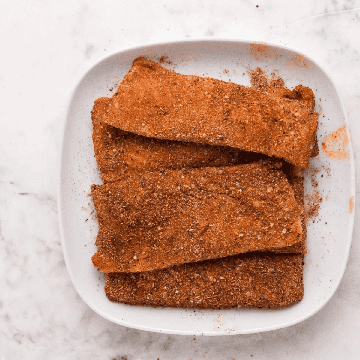 Seasoned salmon fillet resting in an air fryer basket before cooking