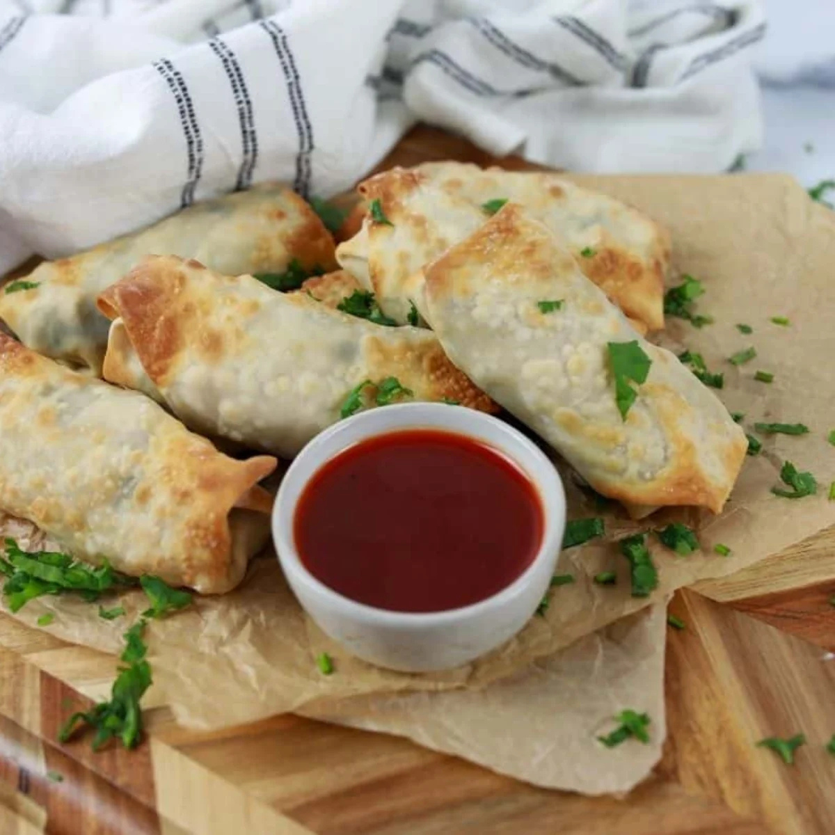 Air fryer chicken cilantro egg rolls stacked on a platter with lime wedges and dipping sauce