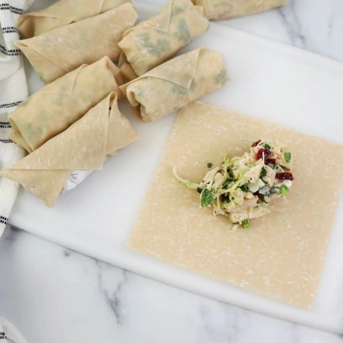 Egg roll wrapper in a diamond position with a log of chicken cilantro filling across the lower third