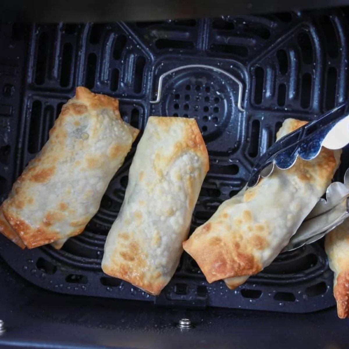Golden blistered egg roll cut in half showing the cilantro and cabbage filling inside