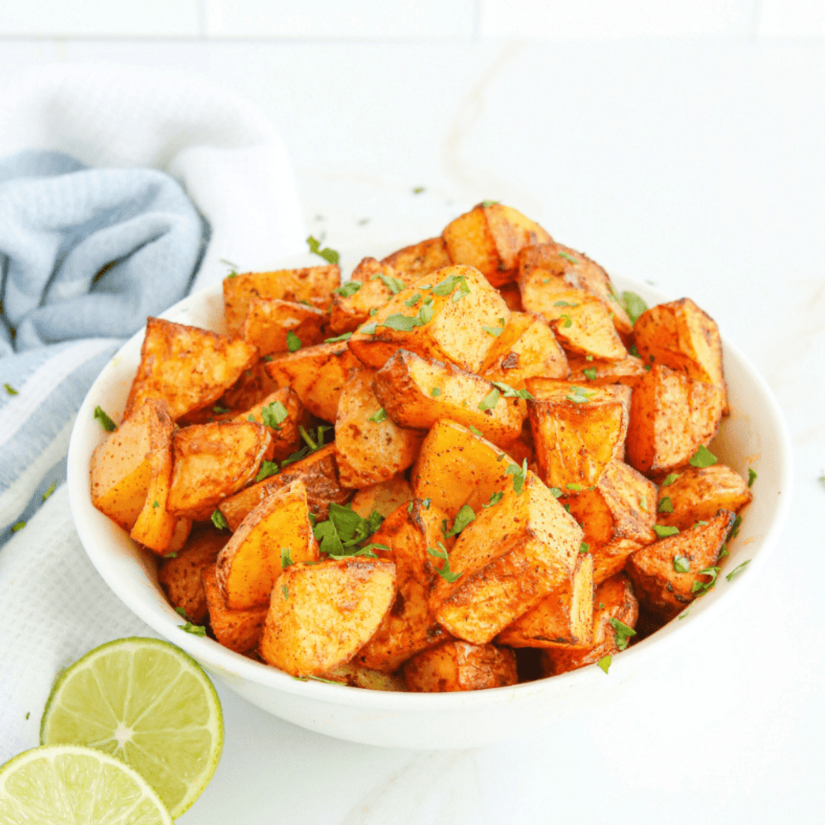 Golden air fryer chili lime potatoes, crispy outside, tender inside, garnished with lime and spices.