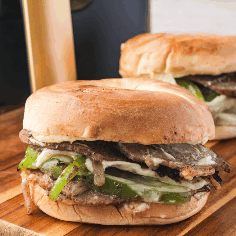 Juicy ribeye steak sandwich topped with grilled onions and melted cheese on a toasted hoagie roll.
