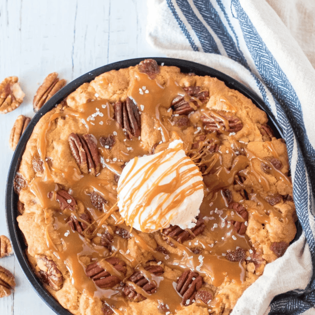 Giant Caramel Pecan Cookie fresh from the air fryer, golden brown with caramel drizzle and pecan pieces on top.