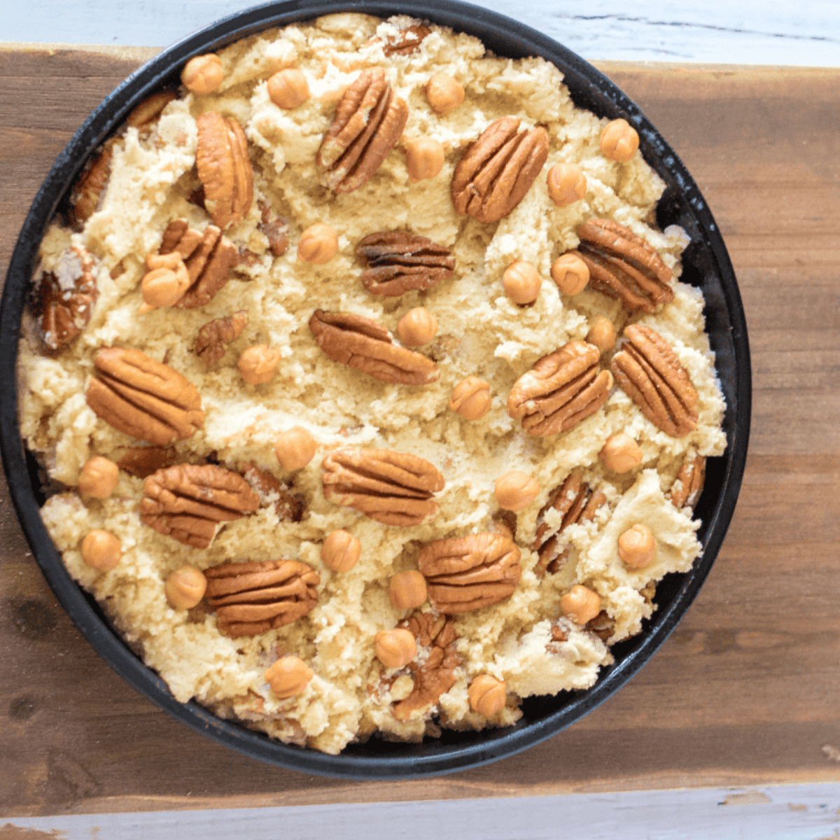 Cookie batter poured into a round pan, cooking in an air fryer until golden and set.