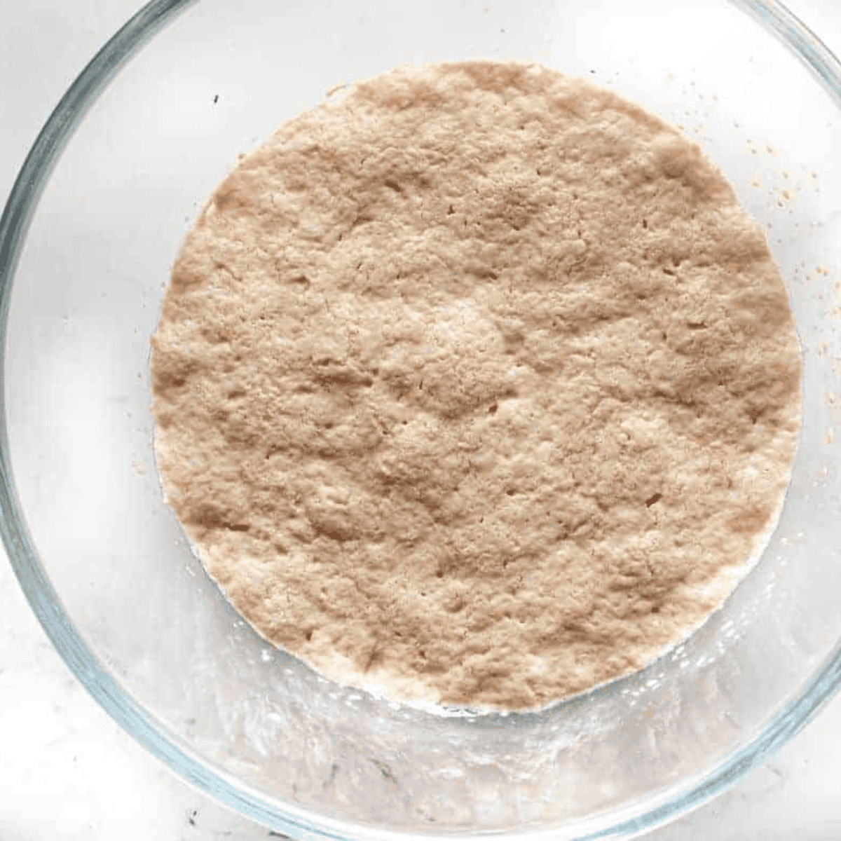 Mixing warm water, yeast, and sugar in a bowl, letting it sit until bubbly to activate the yeast.