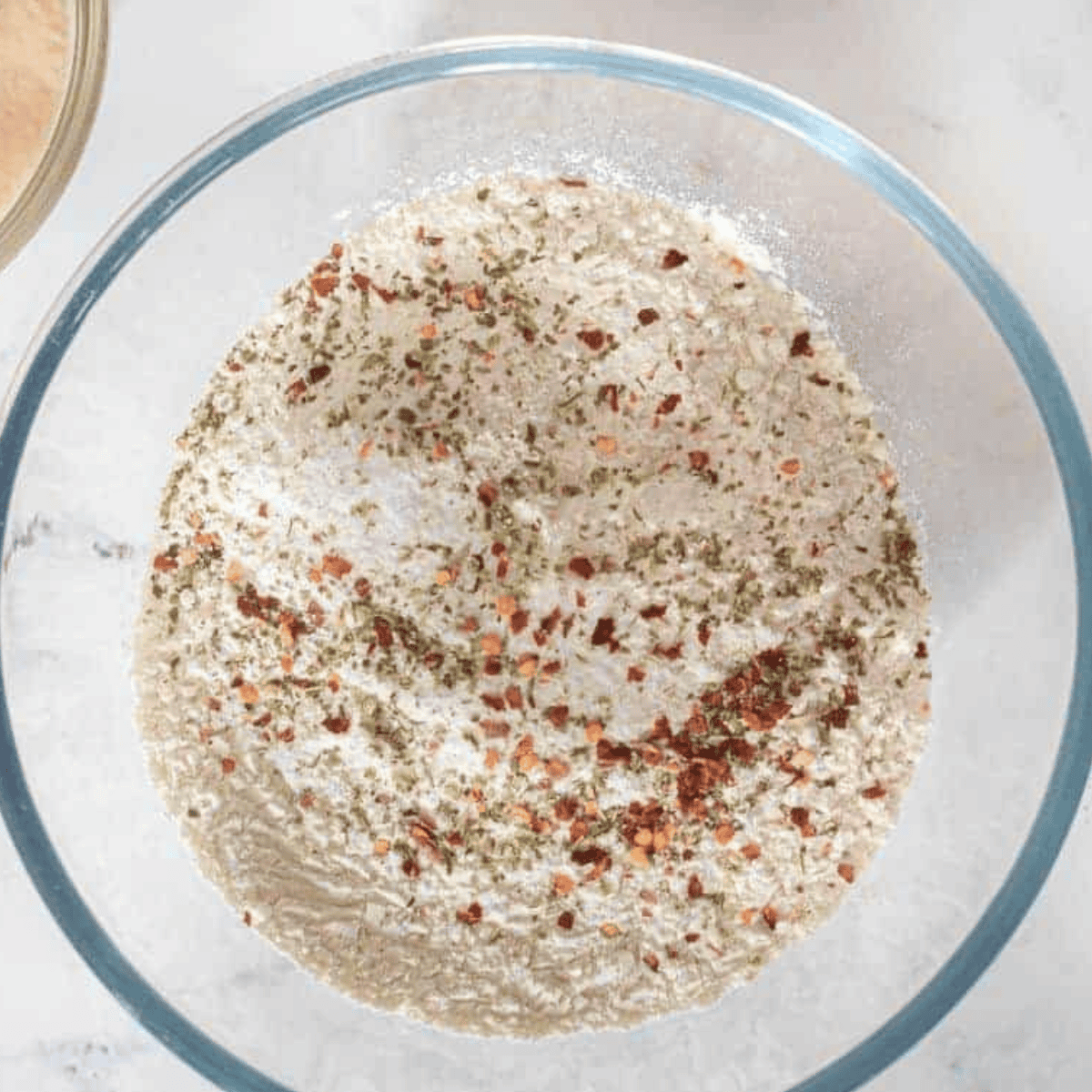 Combining flour, salt, Italian seasoning, chili flakes, and activated yeast mixture to form focaccia dough.