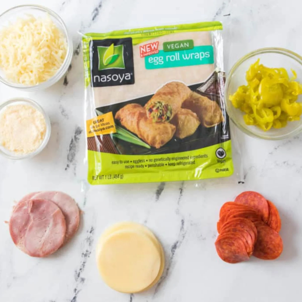Ingredients for air fryer antipasto egg rolls: egg roll wrappers, provolone, deli ham, pepperoni, shredded mozzarella and pepperoncini