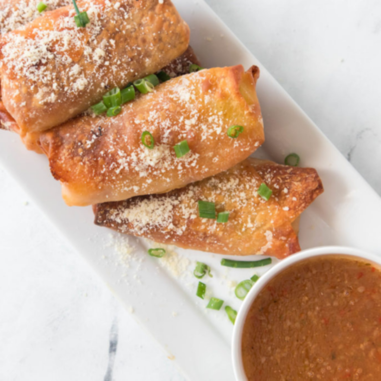 Air fryer antipasto egg rolls resting on a plate after cooking, golden and blistered