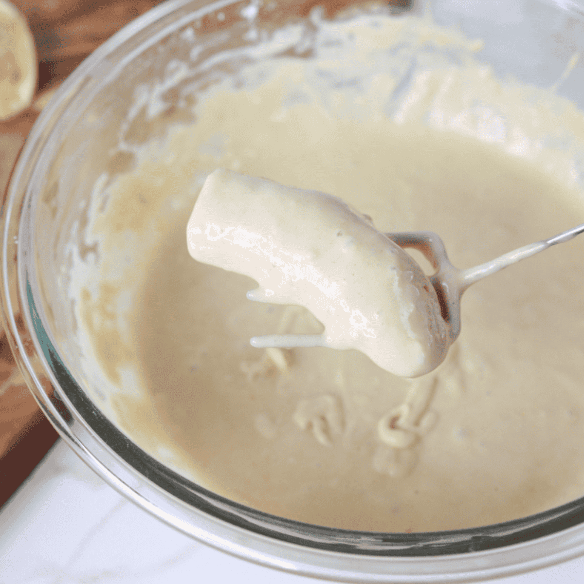 Slicing bananas horizontally and dipping them into pancake batter before placing on parchment paper.
