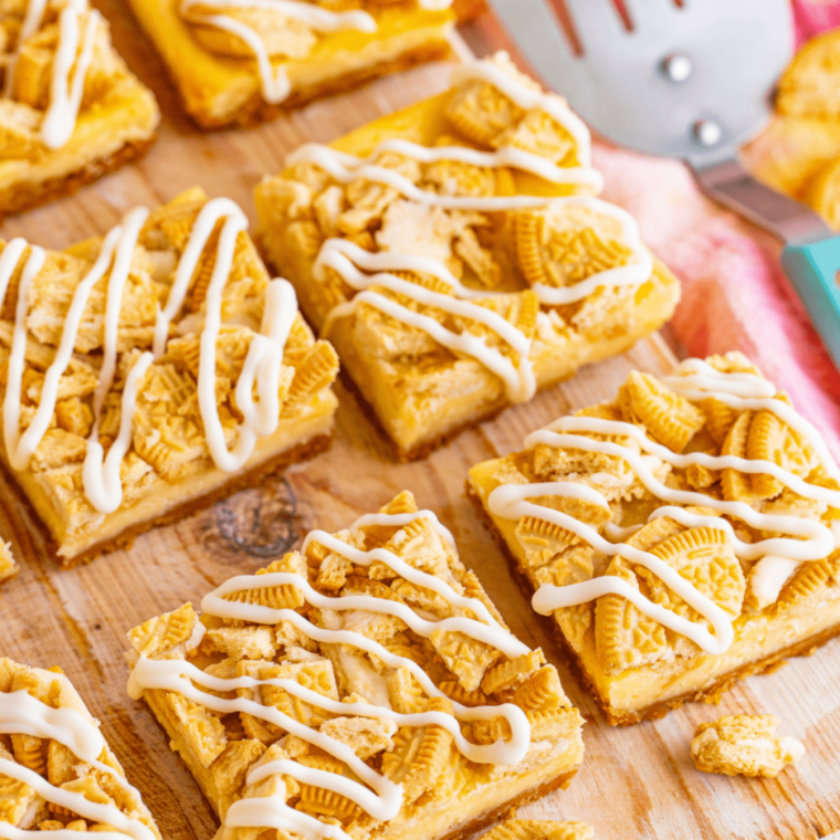 Stack of three golden Oreo air fryer cheesecake bars with white chocolate drizzle