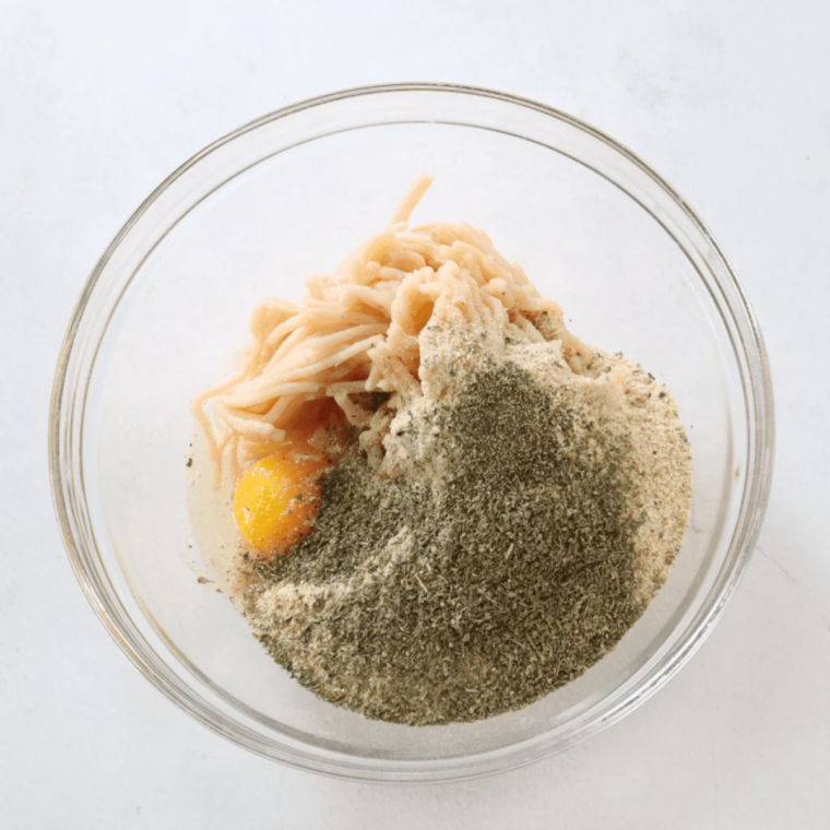 Ground chicken meatball mixture combined with Parmesan, egg and herbs in a mixing bowl