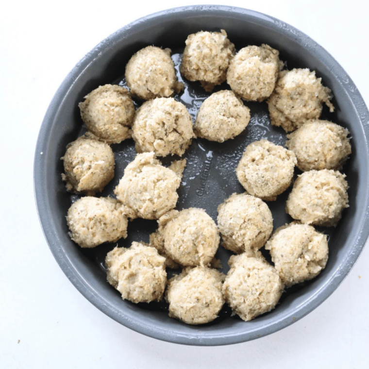 Raw chicken meatballs rolled and spaced in a single layer in an air fryer basket