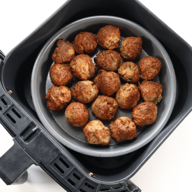 Cooked air fryer chicken meatballs browned and crisp in the basket after 12 minutes