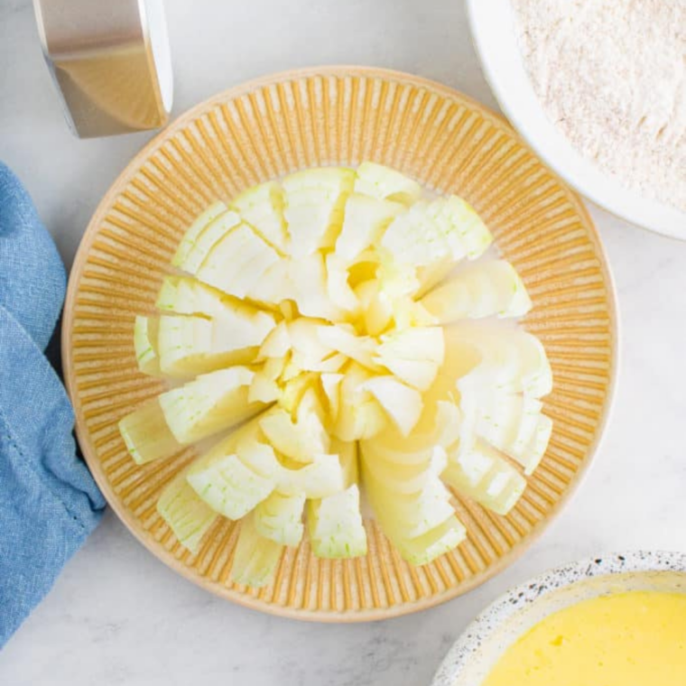 Sweet onion cut into petals and bloomed open, ready to bread for an air fryer bloomin' onion