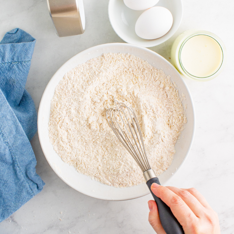 Whisking seasoned flour in a white bowl for the air fryer bloomin' onion coating
