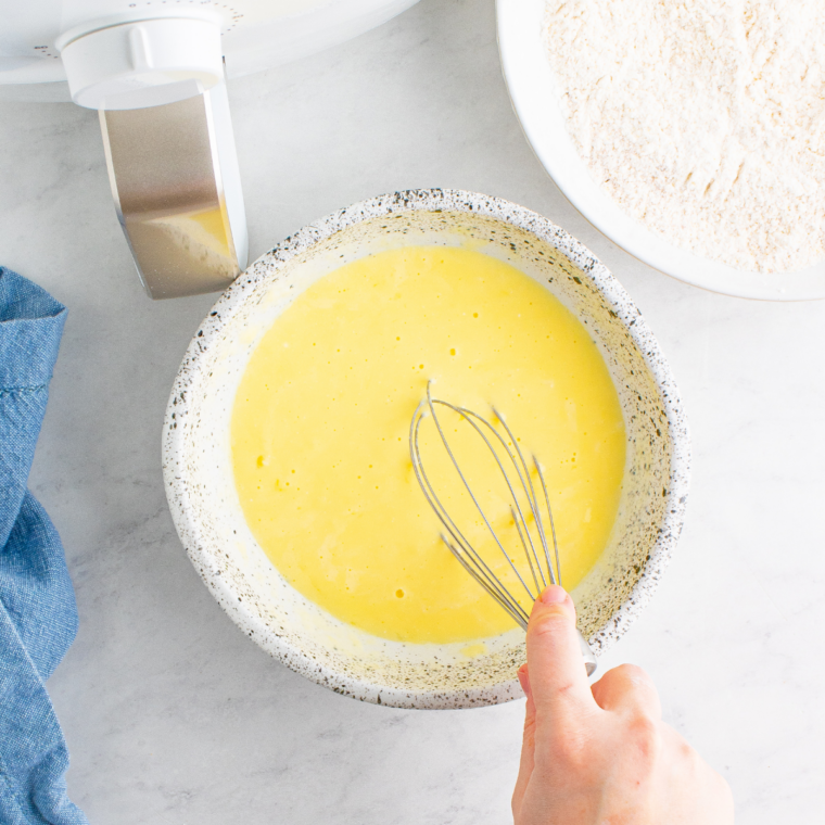 Whisking eggs and buttermilk in a white bowl for the bloomin' onion egg wash