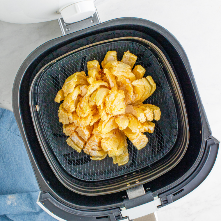 Whisking eggs and buttermilk in a white bowl for the bloomin' onion egg wash
