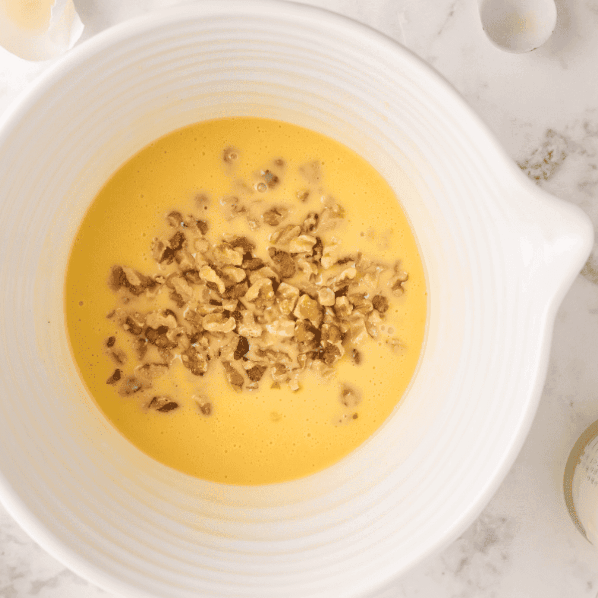 Stirring eggnog, vanilla, chopped walnuts, and baking soda into the mixture