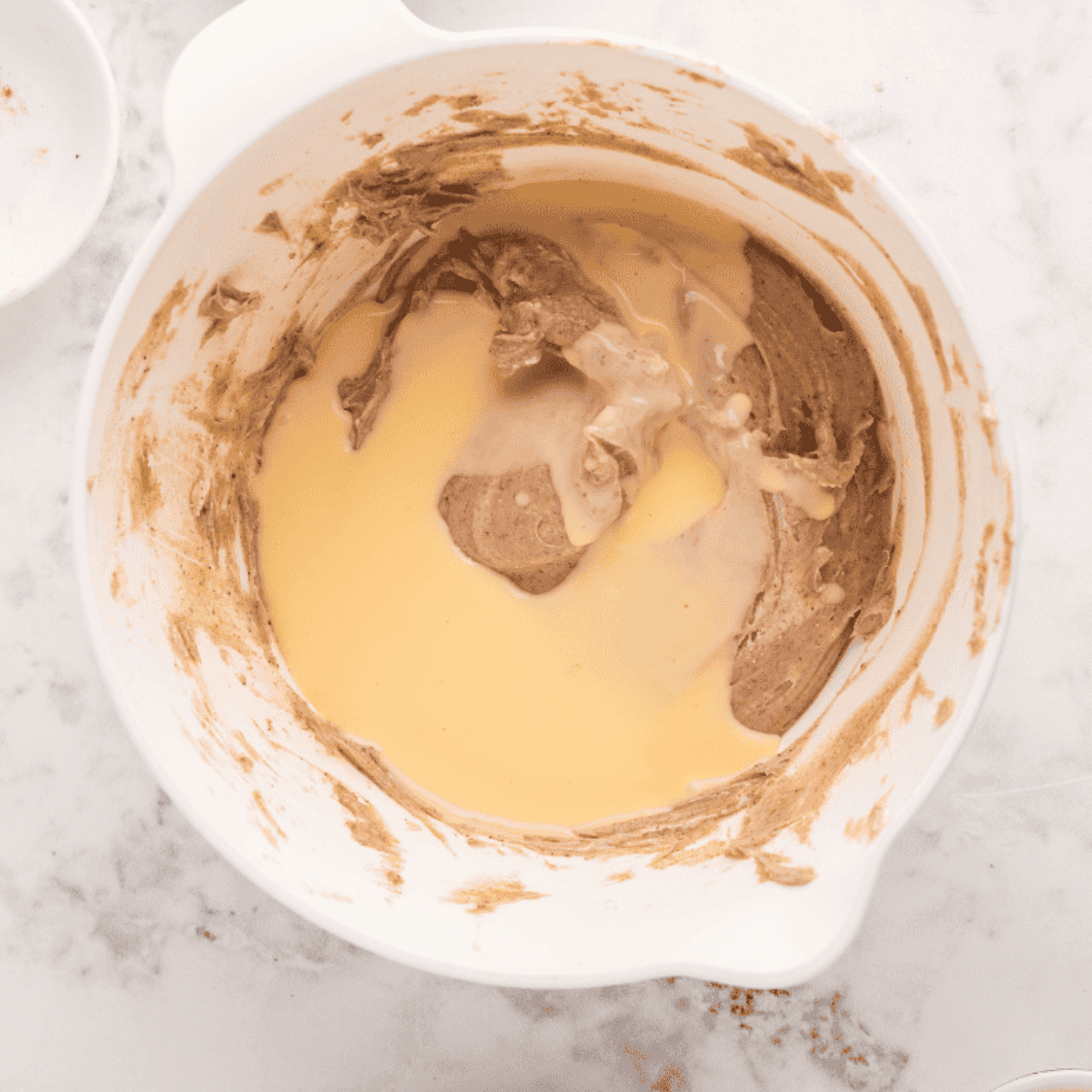 Mixing cream cheese, powdered sugar, nutmeg, cinnamon, and eggnog with a hand mixer until smooth for frosting