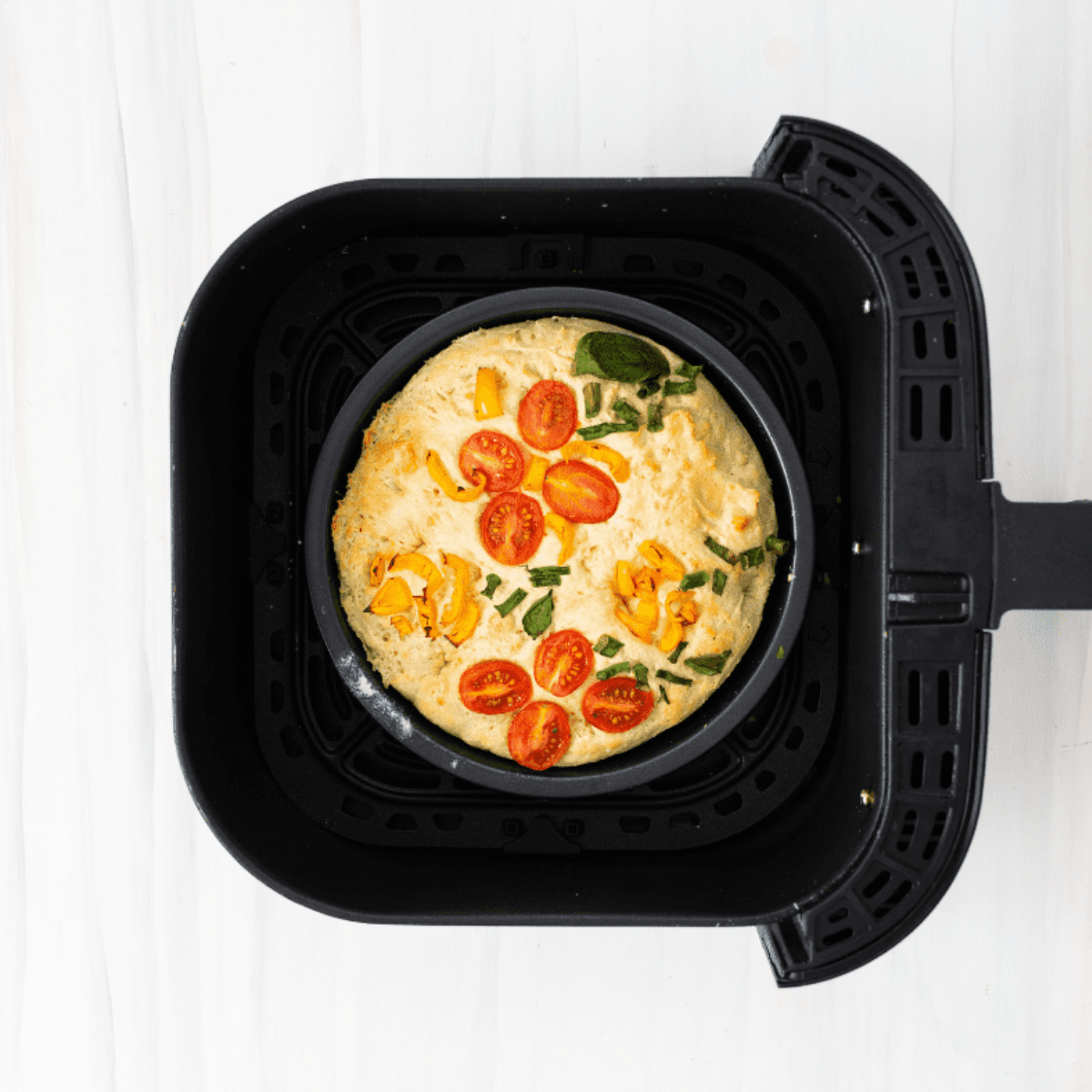 Air fryer focaccia topped with tomatoes, bell peppers, chives, and a decorative vegetable flower pattern