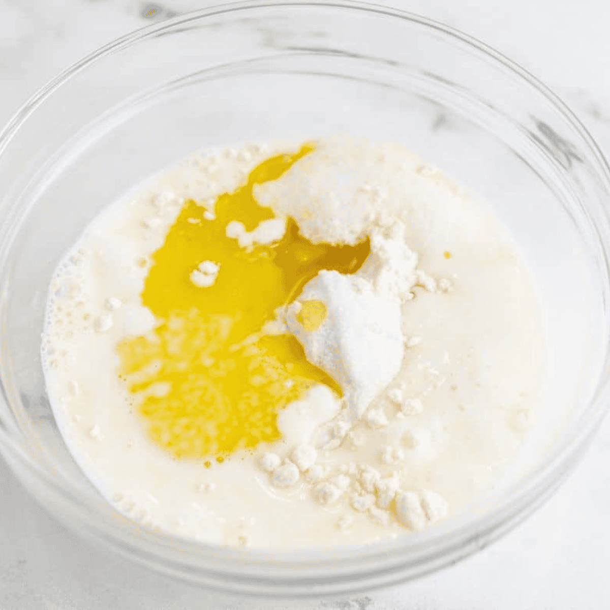 Whisking flour, baking powder, baking soda, salt, milk, and olive oil in a mug until smooth