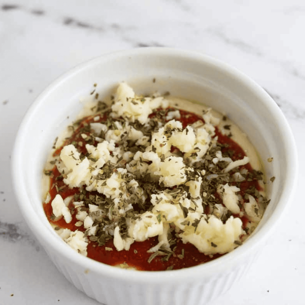 Pressed mug pizza batter forming crust, topped with sauce, cheese, and toppings