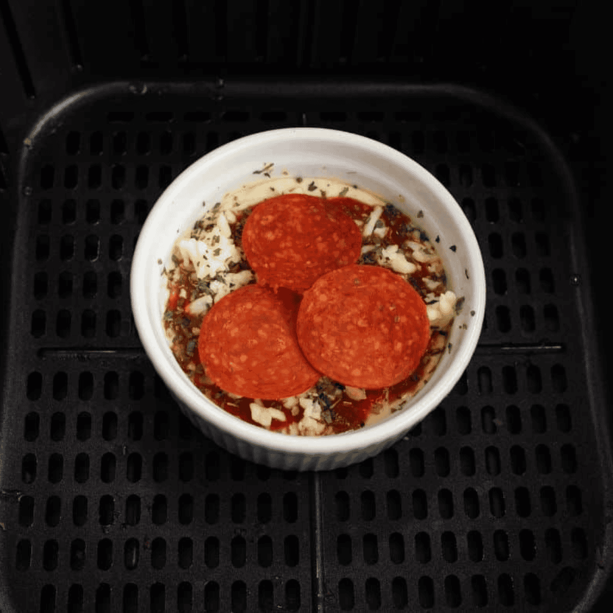 Mug pizza in air fryer basket cooking at 375°F until crust is golden and cheese melted