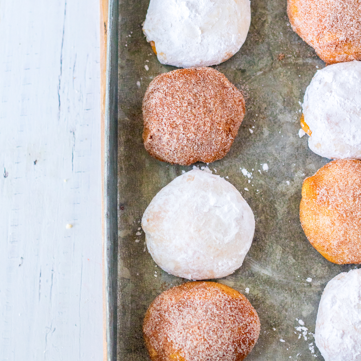 Air fryer pumpkin cheesecake donut holes rolled in cinnamon sugar stacked on a white plate.