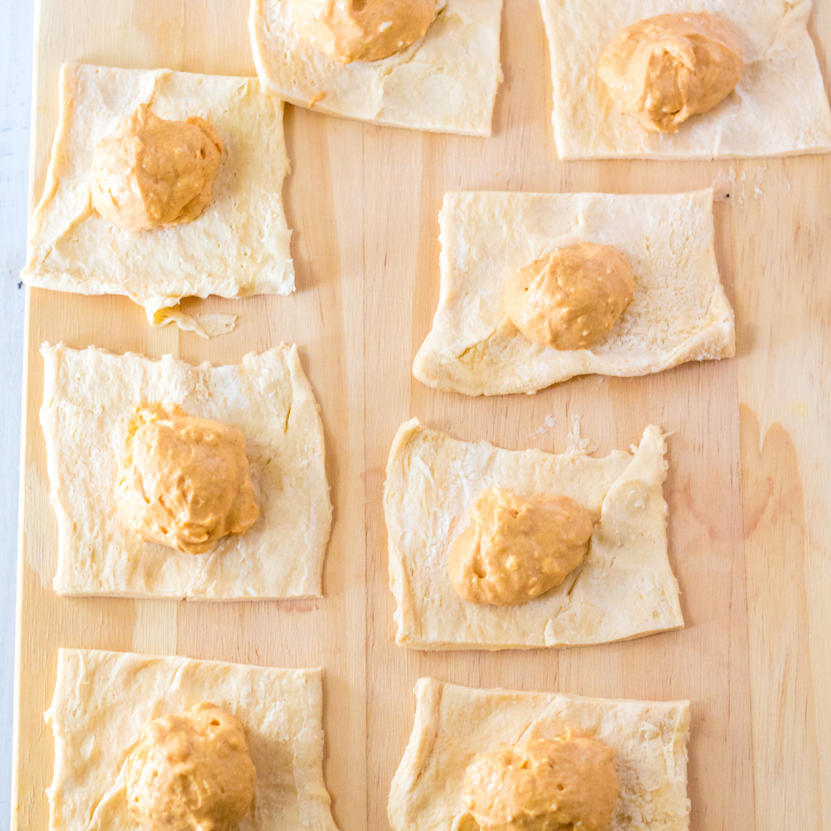 A spoonful of pumpkin cheesecake filling placed in the center of a crescent roll square