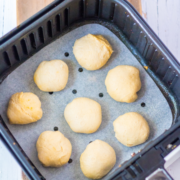 Uncooked pumpkin cheesecake donut holes arranged in a single layer in the air fryer basket
