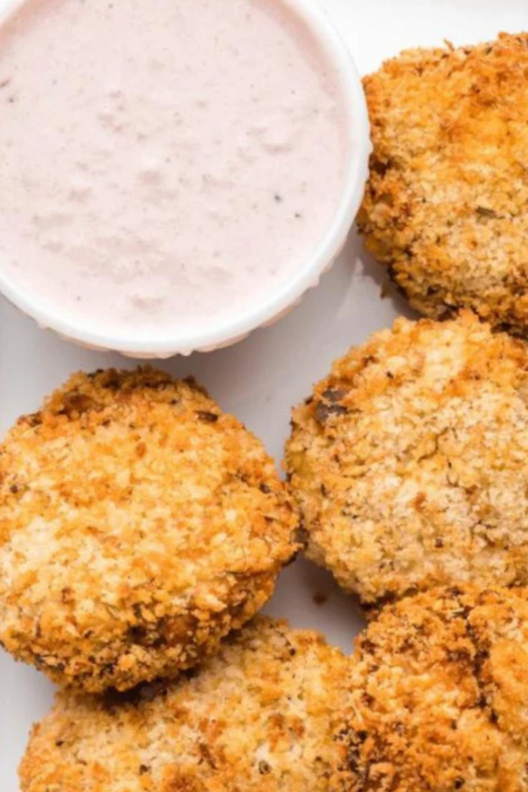 Cranberry dip in a small bowl surrounded by crispy fritters on a wooden board