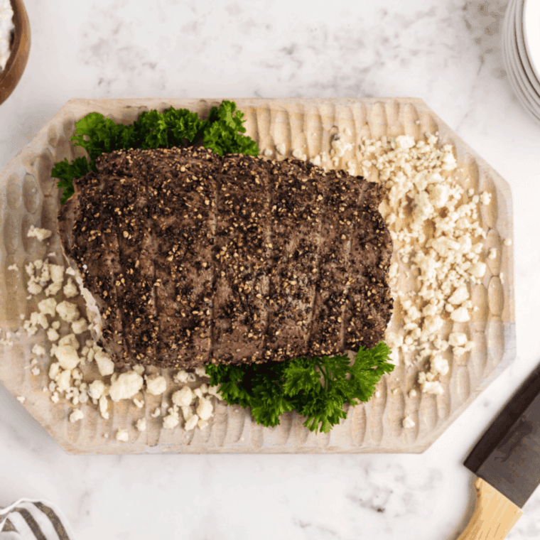 Sliced Black and Blue steak showing a dark, nearly black crust and a cool, bright red interior (blue-rare), served on a white plate.