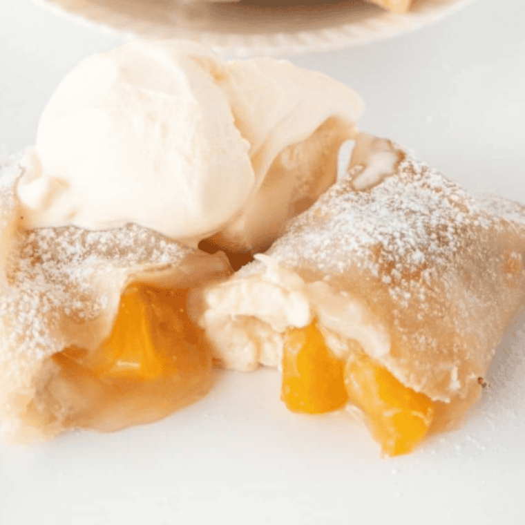 Golden, crispy air fryer peach cobbler egg rolls with bubbling peach filling